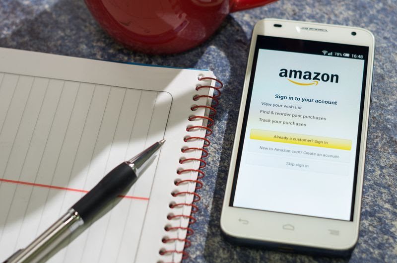 amazon seller accounting (1) - A pen on top of a notepad beside a mobile phone with Amazon sign in page 