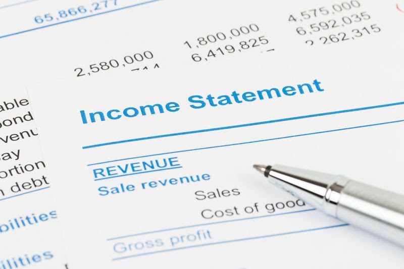 income statement with a pen pointed on the word revenue